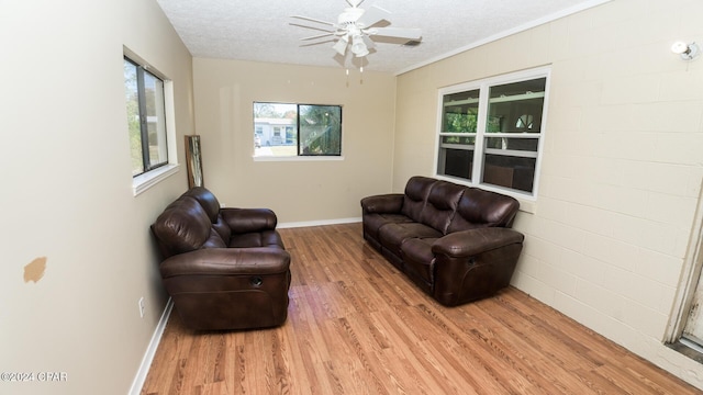 living room featuring hardwood / wood-style flooring, ceiling fan, crown molding, and a textured ceiling