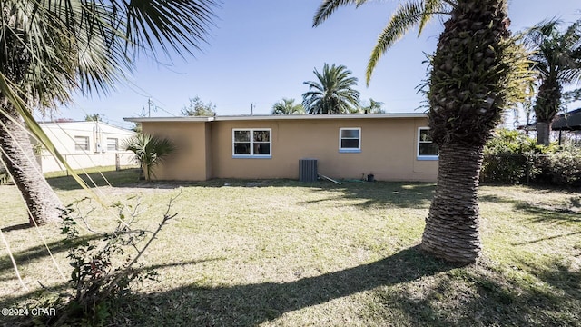 back of house with cooling unit and a lawn