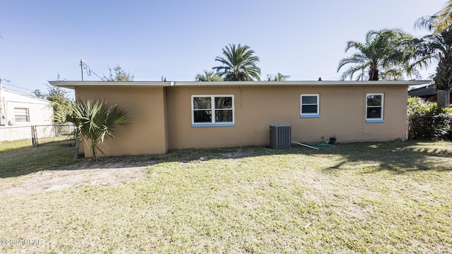 rear view of property with cooling unit and a lawn