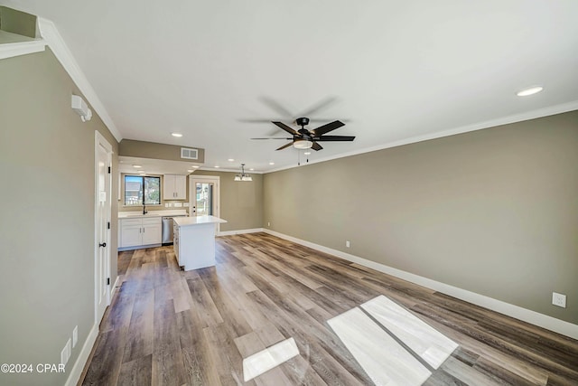 unfurnished living room with light hardwood / wood-style floors, ceiling fan, crown molding, and sink