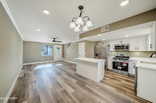 kitchen featuring white cabinets, ceiling fan with notable chandelier, hanging light fixtures, light hardwood / wood-style flooring, and appliances with stainless steel finishes