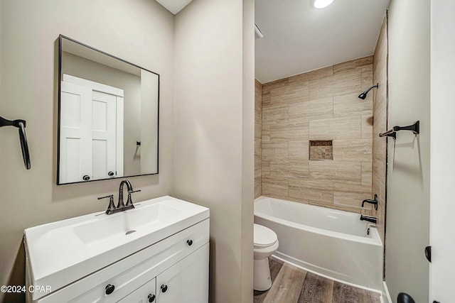 full bathroom with vanity, wood-type flooring, tiled shower / bath combo, and toilet