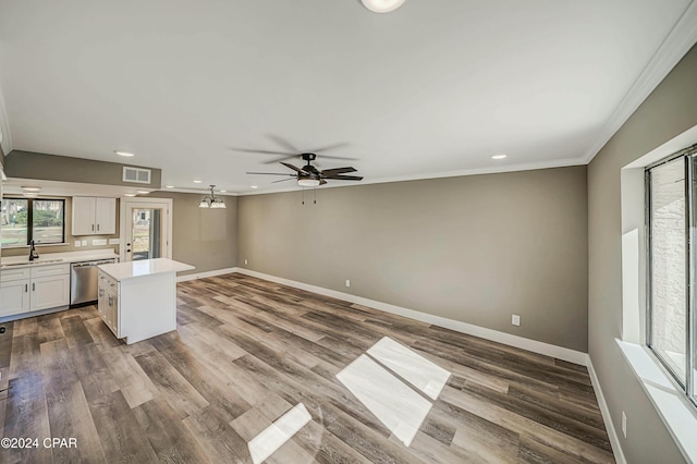 unfurnished living room featuring hardwood / wood-style floors, ceiling fan, crown molding, and sink