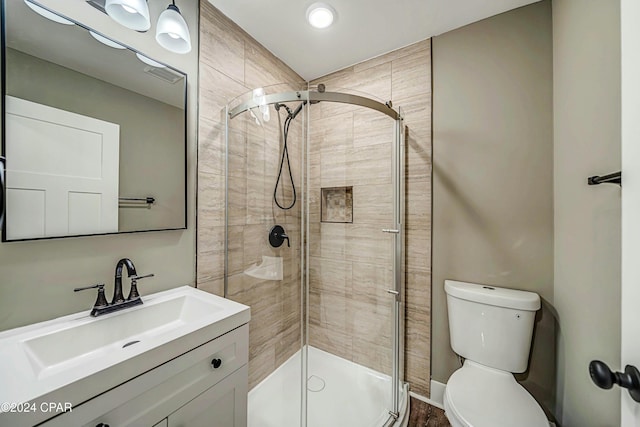 bathroom featuring vanity, toilet, and a shower with shower door