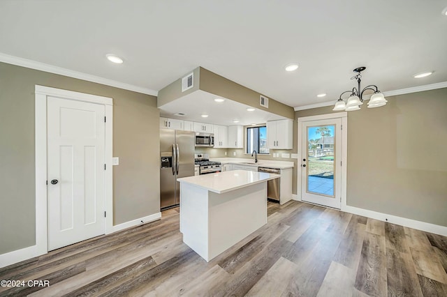 kitchen with white cabinetry, a center island, stainless steel appliances, pendant lighting, and light wood-type flooring