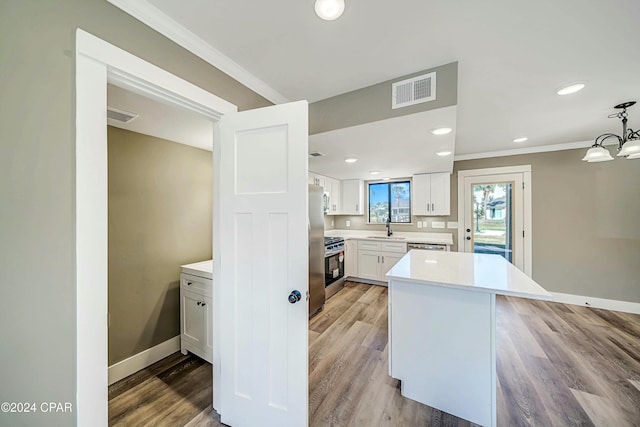 kitchen with white cabinetry, light hardwood / wood-style flooring, crown molding, and decorative light fixtures