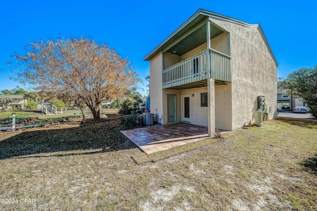 rear view of house featuring a balcony, a patio area, and central air condition unit