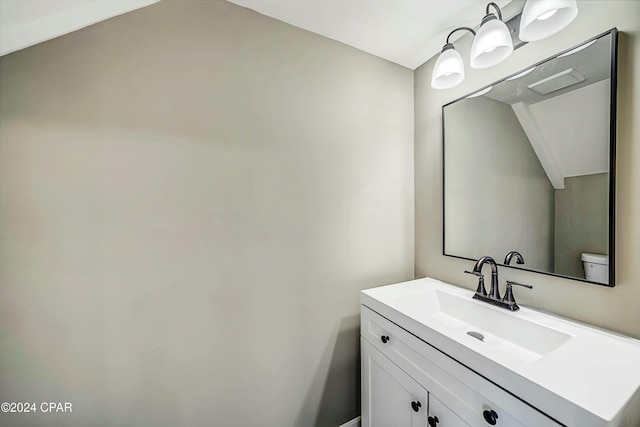 bathroom with vanity, toilet, and lofted ceiling