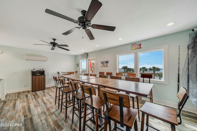 dining area featuring light wood-type flooring, a wall unit AC, and ceiling fan