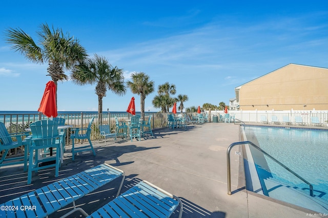 view of swimming pool featuring a water view and a patio