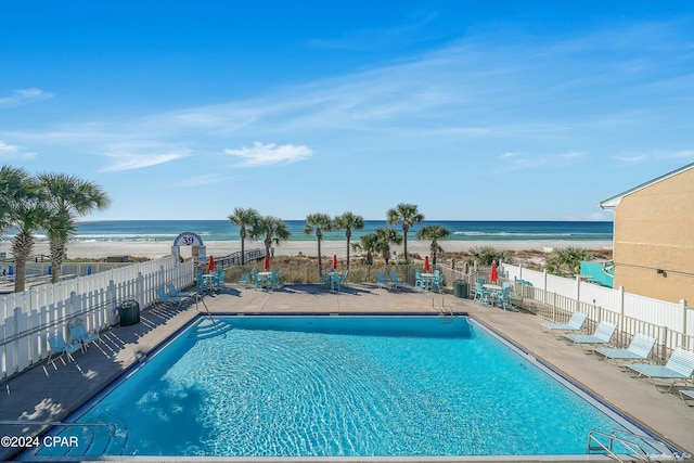 view of pool featuring a beach view, a patio, and a water view