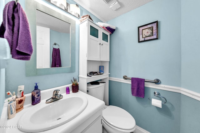 bathroom featuring a textured ceiling, vanity, and toilet