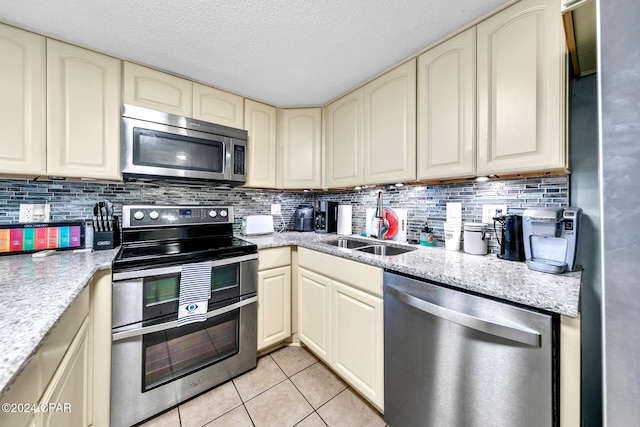 23223 Front Beach Rd Unit 713, Panama City Beach, FL 32413 - kitchen featuring appliances with stainless steel finishes, cream cabinetry, a sink, light tile patterned floors, and a textured ceiling