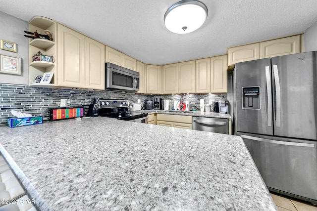 23223 Front Beach Rd Unit 713, Panama City Beach, FL 32413 - kitchen with appliances with stainless steel finishes, cream cabinets, decorative backsplash, a textured ceiling, and a sink