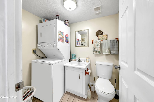 half bath with vanity, visible vents, stacked washer and clothes dryer, a textured ceiling, and toilet