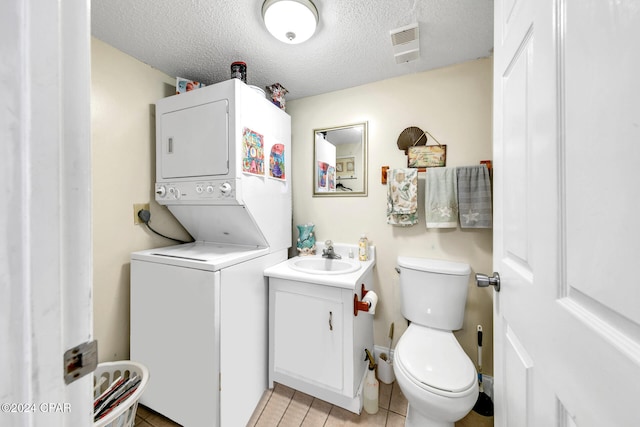 23223 Front Beach Rd Unit 713, Panama City Beach, FL 32413 - half bathroom featuring estacked washer and dryer, vanity, tile patterned floors, toilet, and a textured ceiling