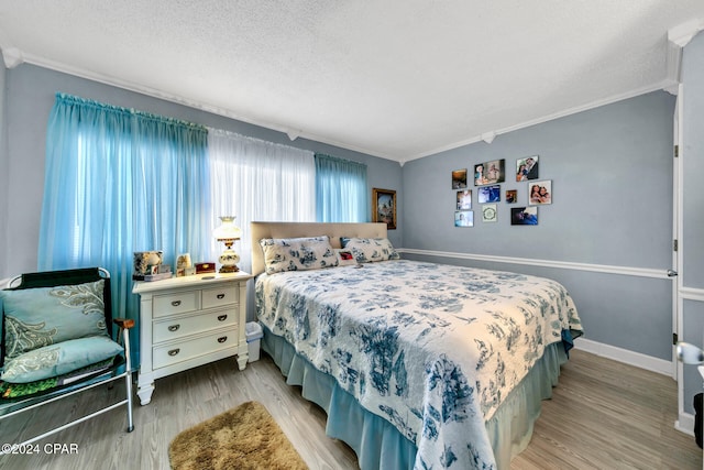 bedroom featuring a textured ceiling, crown molding, and wood finished floors