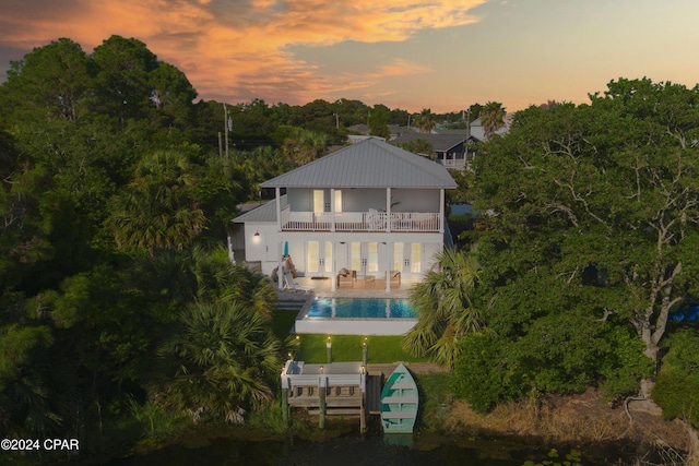 back house at dusk with a balcony and a patio