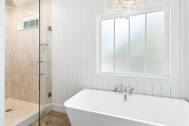 bathroom with shower with separate bathtub, an inviting chandelier, and a wealth of natural light