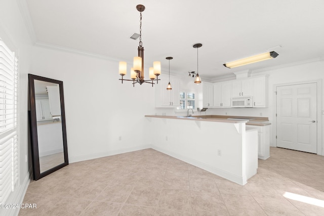 kitchen featuring a breakfast bar, kitchen peninsula, ornamental molding, decorative light fixtures, and white cabinetry