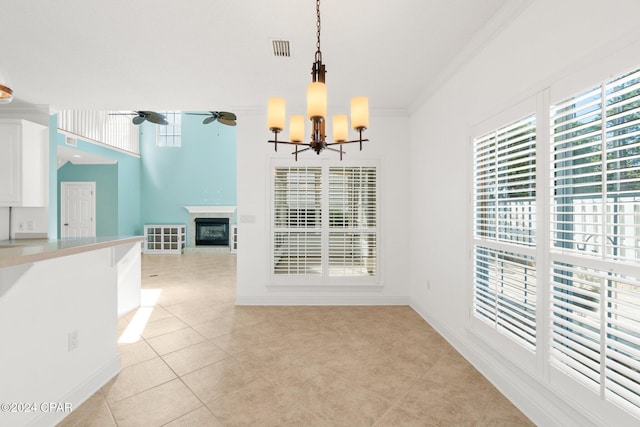 unfurnished dining area featuring ceiling fan with notable chandelier, ornamental molding, and light tile patterned floors