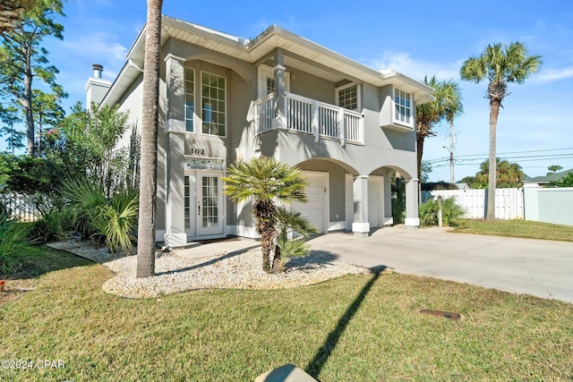 view of front of property with a garage, a balcony, and a front lawn