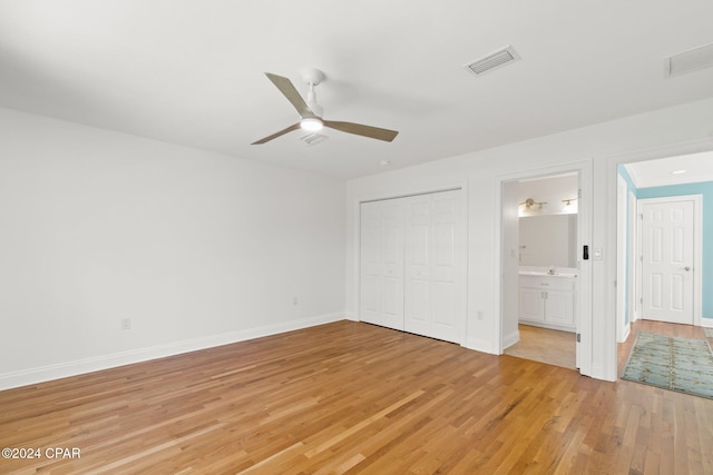 unfurnished bedroom featuring a closet, light hardwood / wood-style flooring, ceiling fan, and ensuite bathroom