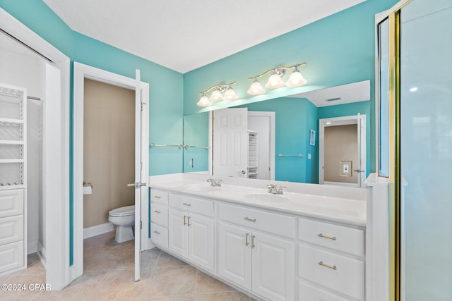 bathroom with tile patterned floors, vanity, a textured ceiling, and toilet