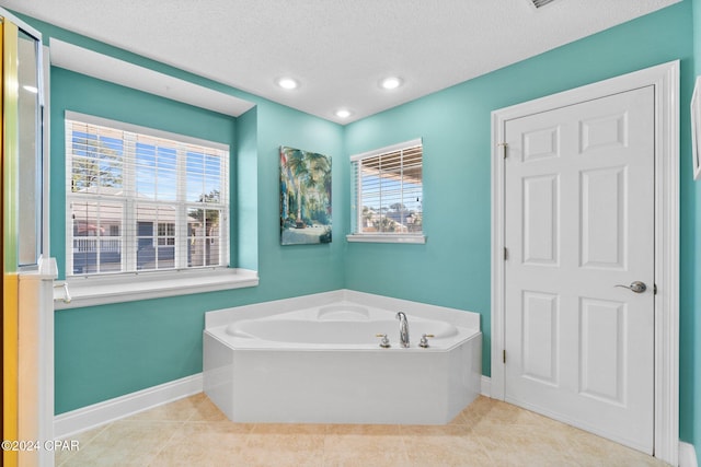 bathroom featuring tile patterned floors, a tub, and a textured ceiling