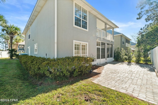 back of property with a yard, a balcony, and a patio area