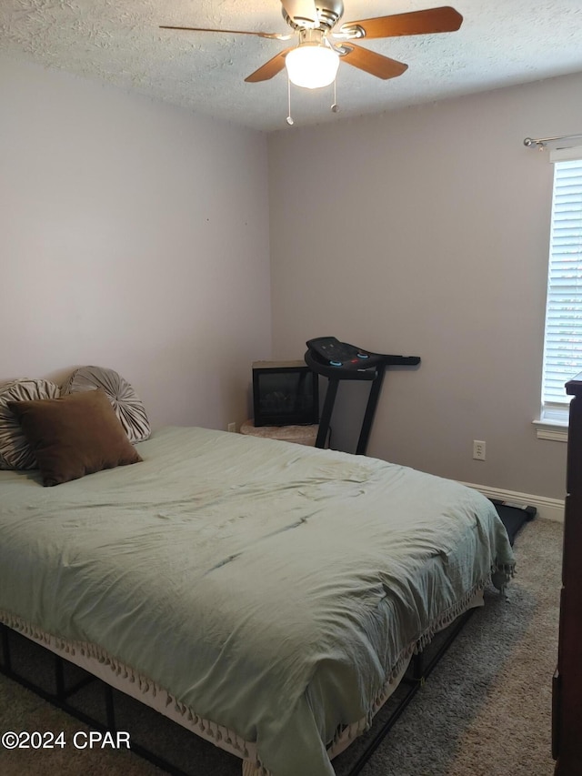 carpeted bedroom with ceiling fan and a textured ceiling