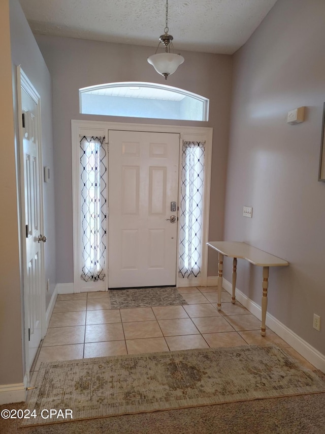 foyer entrance featuring light tile patterned floors and a textured ceiling