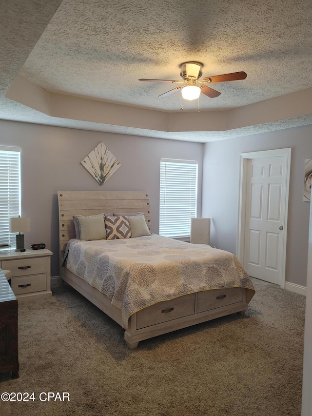 carpeted bedroom featuring ceiling fan and a textured ceiling