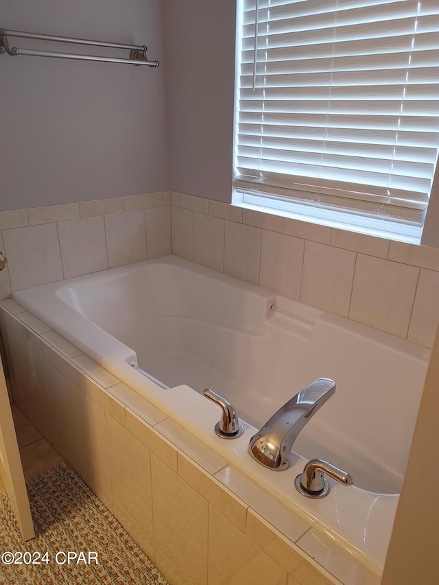 bathroom featuring a healthy amount of sunlight and tiled tub