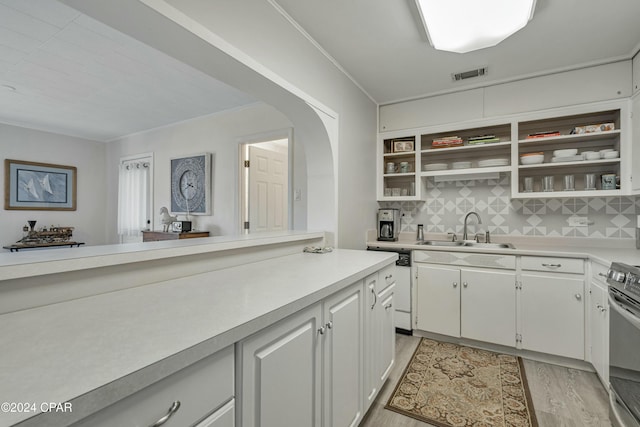 kitchen with white cabinets, decorative backsplash, light hardwood / wood-style floors, and sink