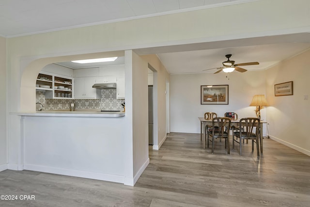 kitchen with crown molding, stainless steel fridge, light wood-type flooring, tasteful backsplash, and white cabinetry