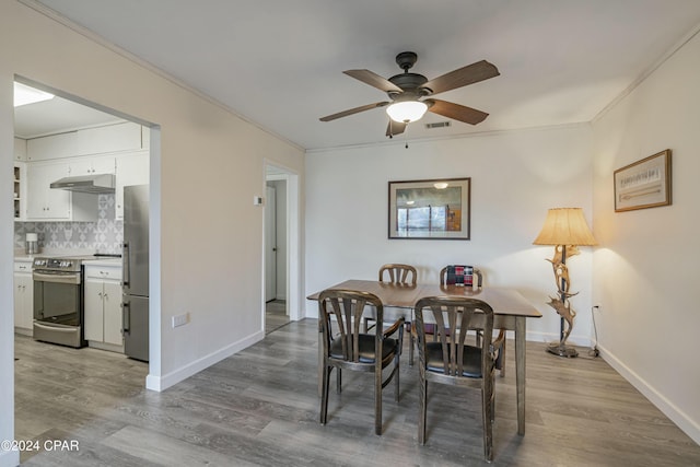 dining room featuring baseboards, wood finished floors, a ceiling fan, and ornamental molding