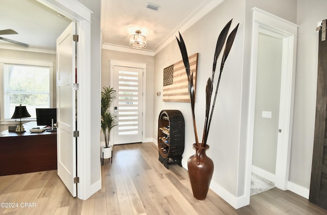 entryway with crown molding and light hardwood / wood-style floors