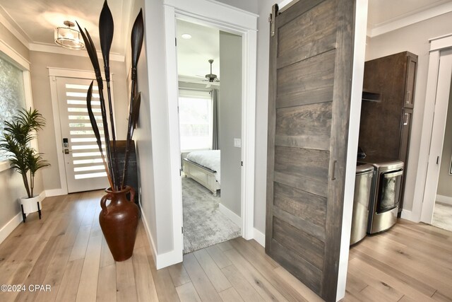 corridor featuring a barn door, light hardwood / wood-style floors, and washing machine and clothes dryer