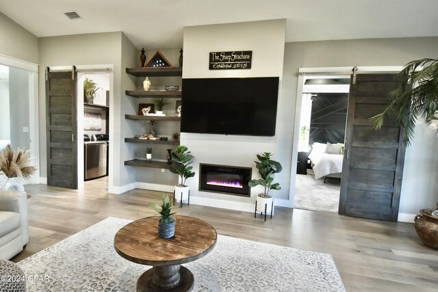 living room with a barn door and light wood-type flooring