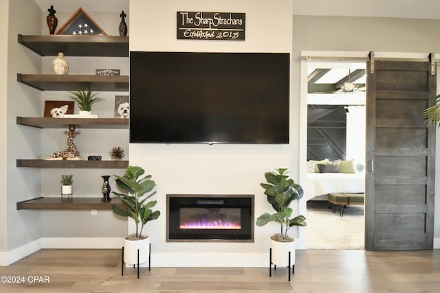 living room with a barn door and light wood-type flooring