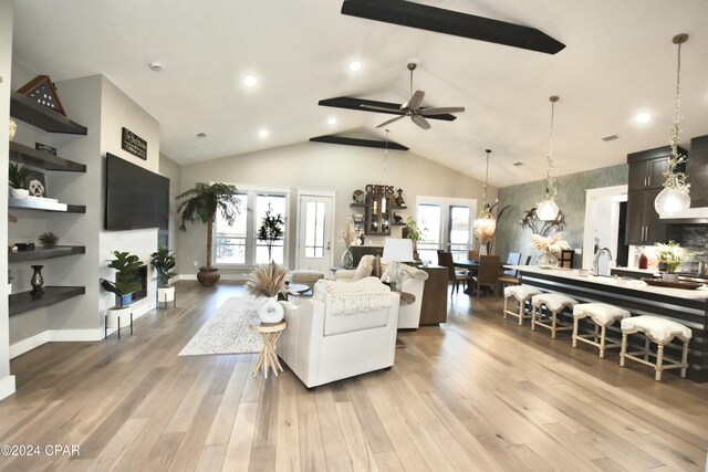 living room featuring ceiling fan, vaulted ceiling, sink, and light hardwood / wood-style flooring