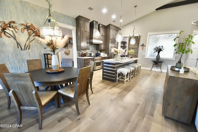 dining space featuring a chandelier, light hardwood / wood-style floors, and vaulted ceiling