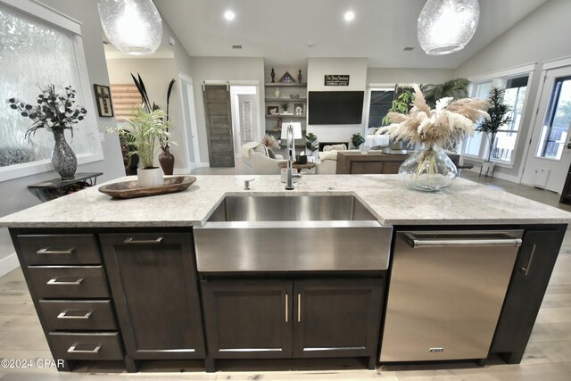 kitchen with a kitchen island with sink, dishwasher, sink, and pendant lighting