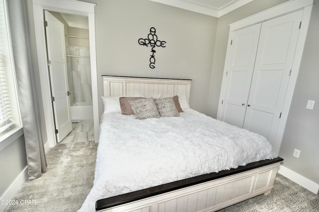 carpeted bedroom with ensuite bath, ornamental molding, and a closet