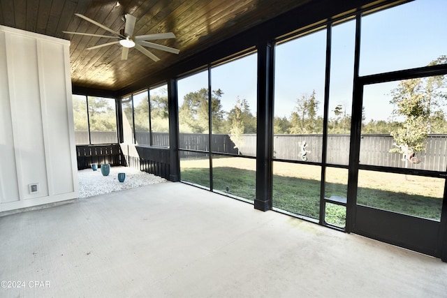 unfurnished sunroom featuring ceiling fan, a healthy amount of sunlight, and wooden ceiling