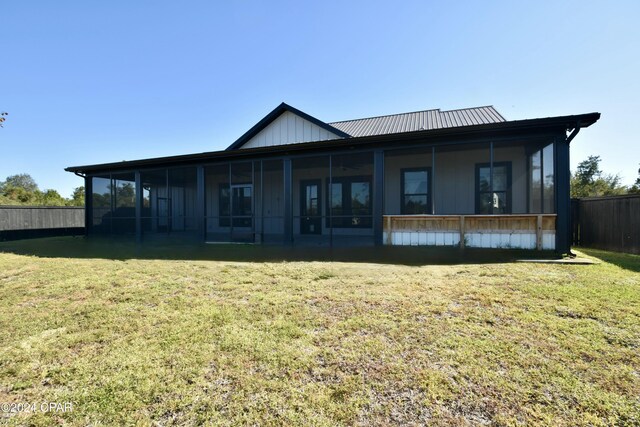 back of property with a yard and a sunroom