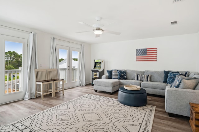 living room featuring hardwood / wood-style floors, french doors, a healthy amount of sunlight, and ceiling fan