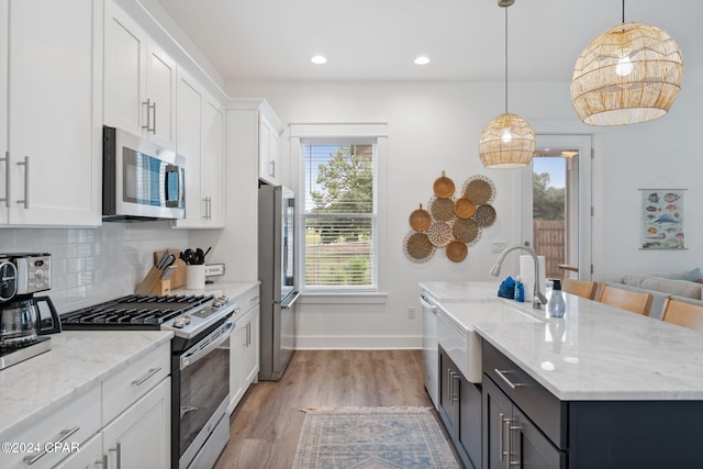 kitchen featuring stainless steel appliances, white cabinetry, a healthy amount of sunlight, and sink