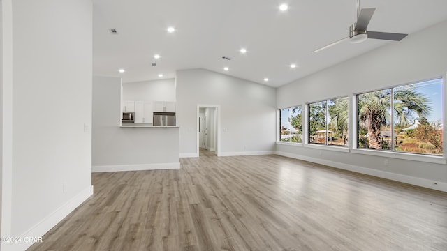 unfurnished living room featuring high vaulted ceiling, light hardwood / wood-style flooring, and ceiling fan